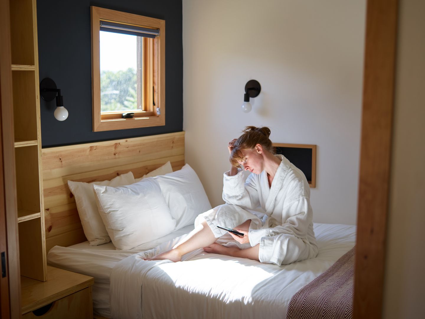 A reader relaxing on a bed with a tablet in soft morning light