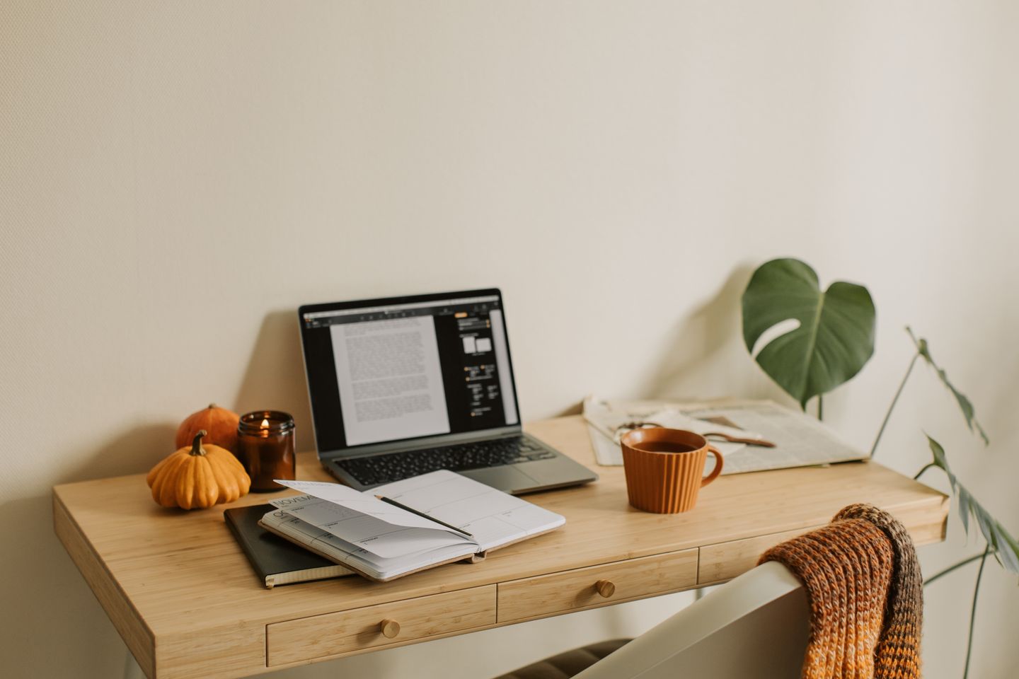 A warm home-office table with a laptop, calendar, and reading materials