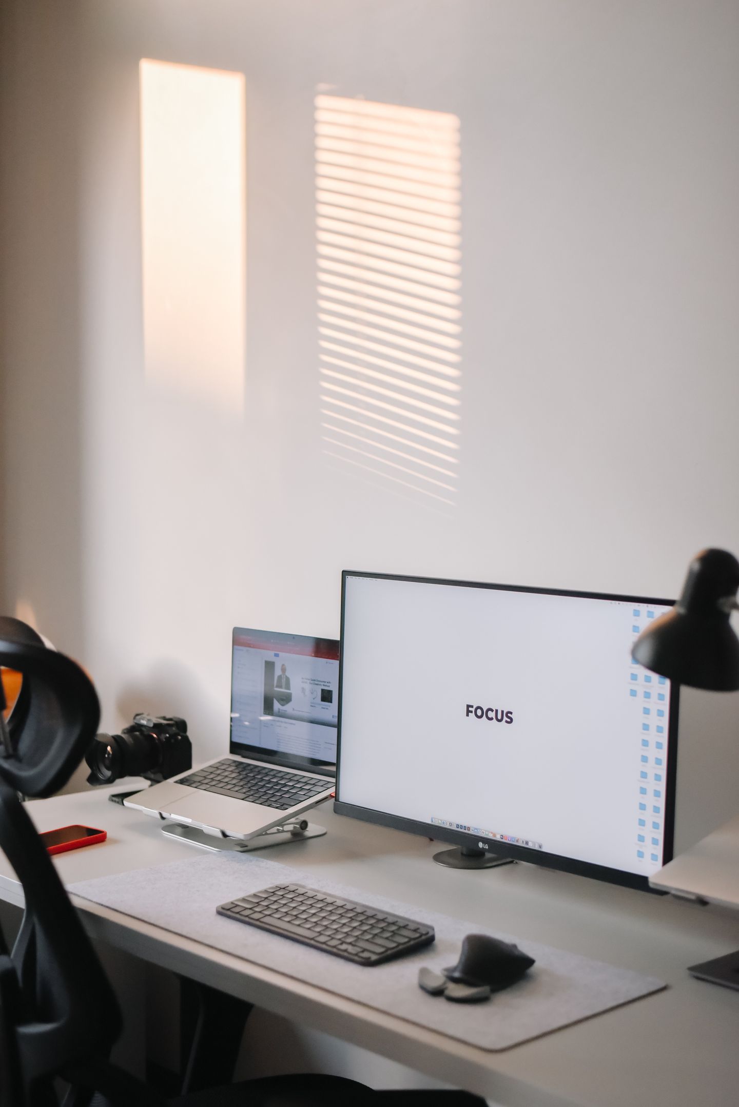 A tidy home office with a monitor, laptop, and camera on a desk