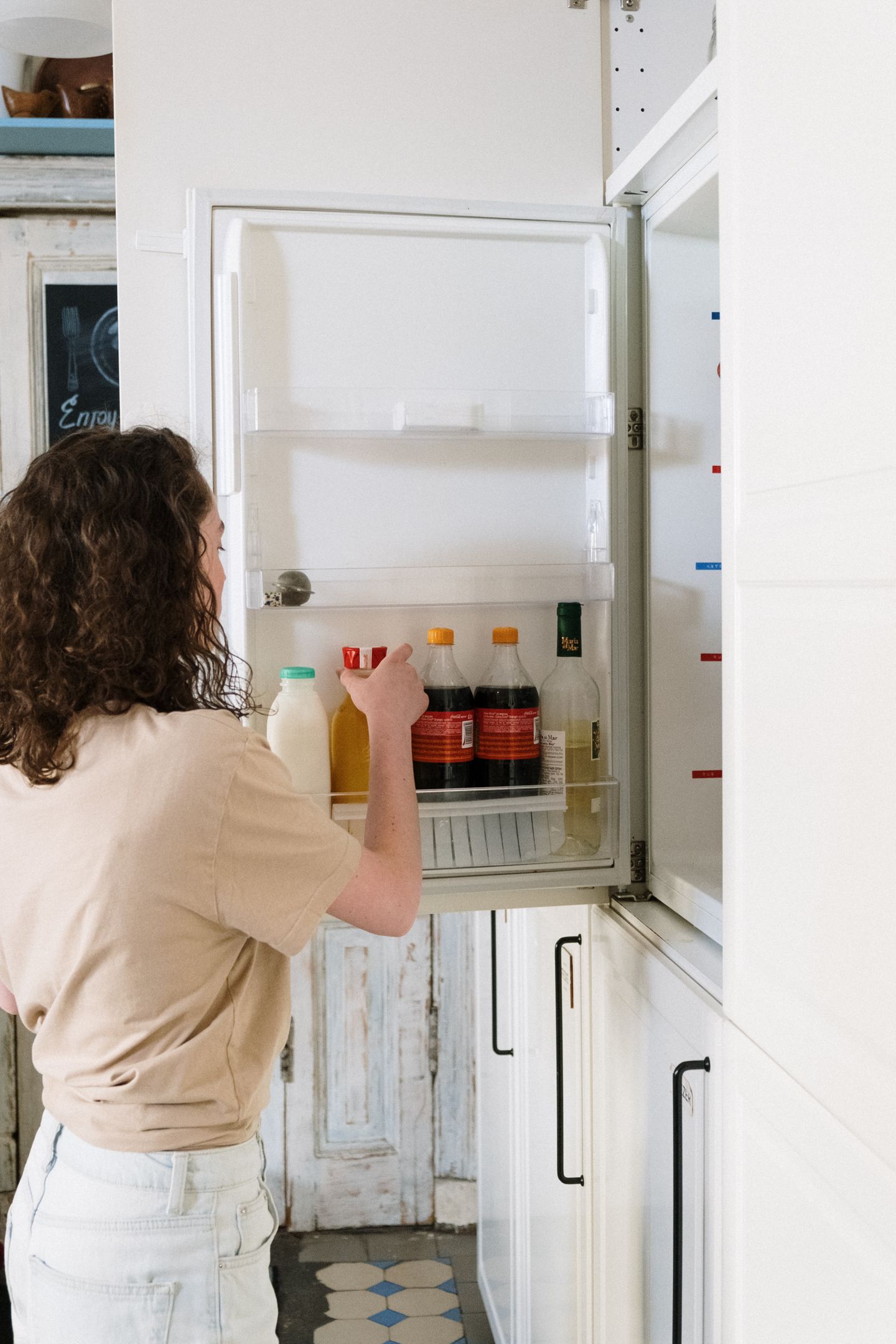 A person choosing a drink from an open refrigerator