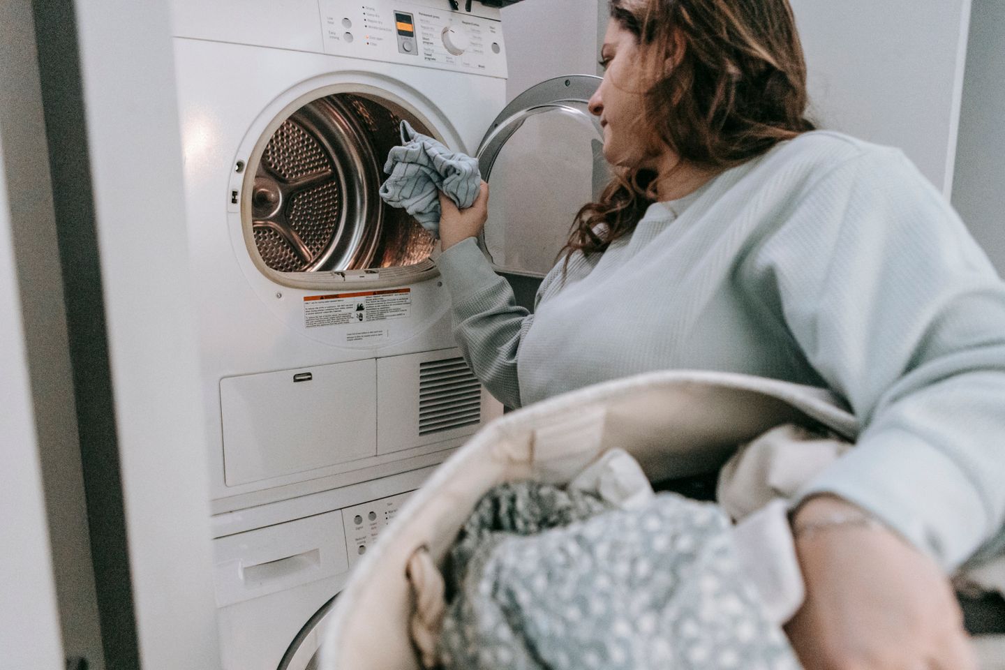 A person loading laundry into a washing machine